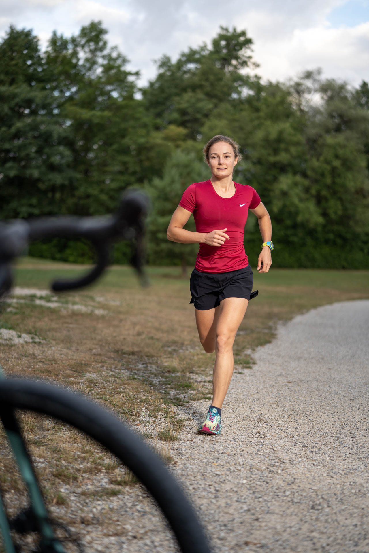 Eine Triathletin beim Laufen am Kuhsee in Augsburg - der See und die Natur sind ihr Trainingspartner.